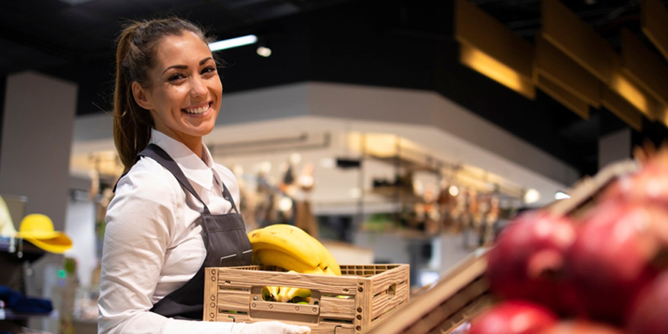 Mujer sonriendo con una cesta en la mano, cogiendo fruta